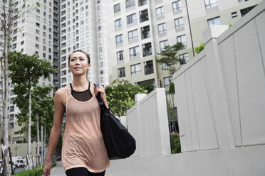 Selbstbewusste, fitte Frau beim Spaziergang in städtischer Umgebung - IGGF00451