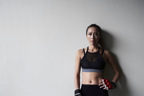 Porträt eines selbstbewussten weiblichen Boxers vor einer grauen Wand - IGGF00464