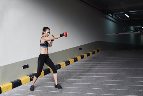 Weiblicher Boxer beim Boxen in einer Garage - IGGF00466