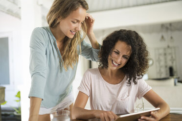 Two smiling women at home using tablet - SBOF01452