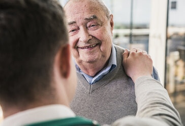 Senior man smiling at young man - UUF12876