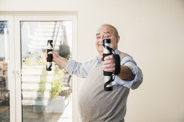 Portrait of smiling senior man doing an arm exercise - UUF12878