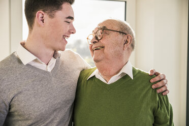 Senior man smiling at young man - UUF12892