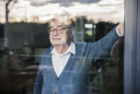 Porträt eines ernsten Mannes, der am Fenster steht und hinausschaut - UUF12911