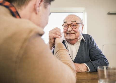 Smiling senior man arm wrestling with young man stock photo