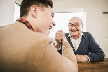 Happy senior man and young man arm wrestling - UUF12916