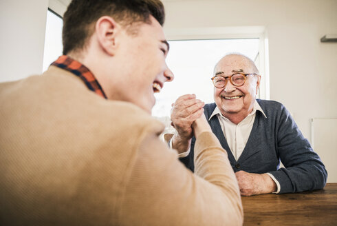 Glücklicher älterer Mann und junger Mann beim Armdrücken - UUF12916