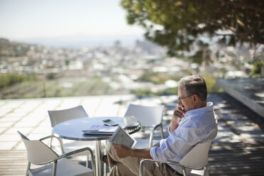 Older man using tablet computer outdoors - CAIF02935