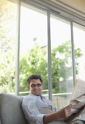 Mann liest Zeitung auf Sofa - CAIF02943