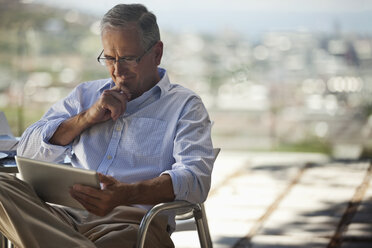 Older man using tablet computer outdoors - CAIF02944