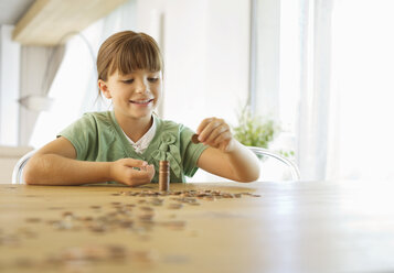 Girl stacking pennies on counter - CAIF02945