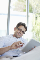 Mann mit Tablet-Computer auf dem Sofa - CAIF02949