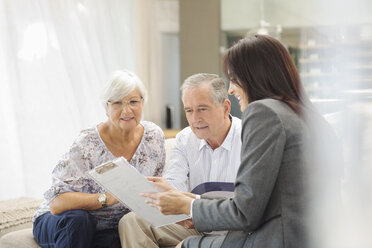 Financial advisor talking to couple on sofa - CAIF02951