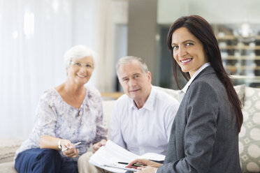 Financial advisor talking to couple on sofa - CAIF02953