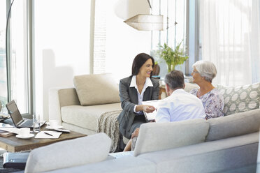 Finanzberater im Gespräch mit einem Paar auf dem Sofa - CAIF02956