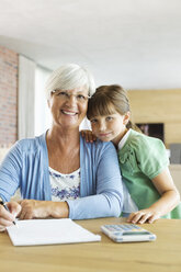 Older woman and granddaughter using calculator - CAIF02957