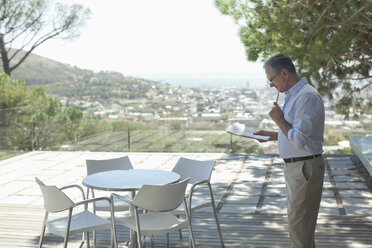 Older man using tablet computer outdoors - CAIF02972