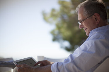 Älterer Mann benutzt Tablet-Computer im Freien - CAIF02980