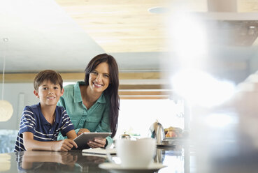 Mother and son using tablet computer in kitchen - CAIF02985