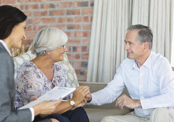 Financial advisor talking to couple on sofa - CAIF02999