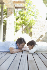 Father and daughter laying on porch - CAIF03009