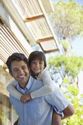 Father carrying daughter piggy back outdoors - CAIF03014