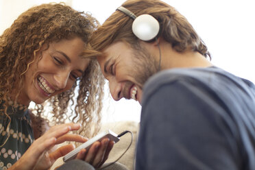 Smiling couple listening to headphones - CAIF03058
