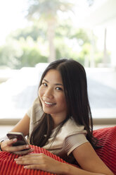 Woman using cell phone on sofa - CAIF03060