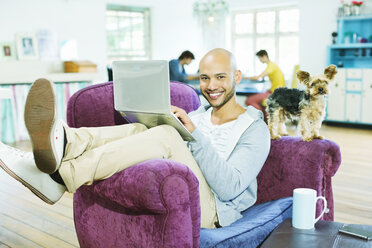 Man using laptop in armchair - CAIF03199