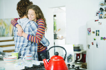 Couple hugging in kitchen - CAIF03204