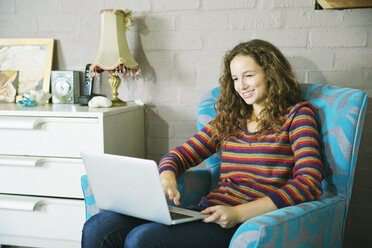 Woman using laptop in armchair - CAIF03209