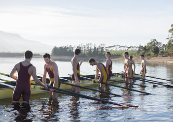 Rowing team placing boat on lake - CAIF03228