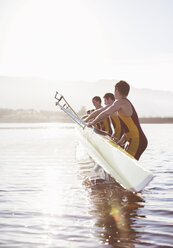 Rowing team placing boat in lake - CAIF03232