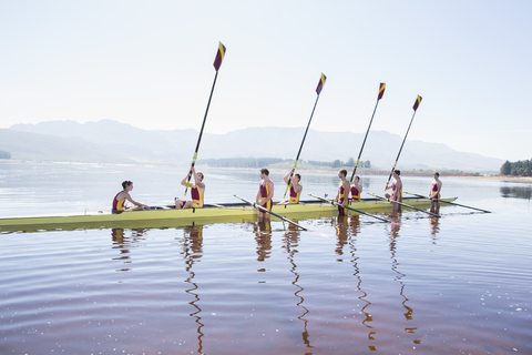 Rudermannschaft mit erhobenen Rudern auf dem See, lizenzfreies Stockfoto