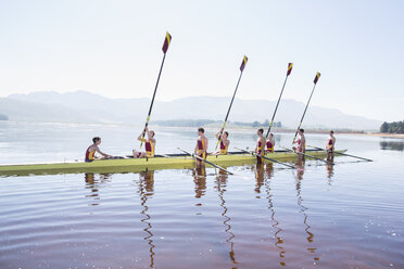 Rowing team with oars raised on lake - CAIF03235