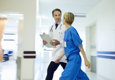 Arzt und Krankenschwester gehen im Krankenhausflur, lizenzfreies Stockfoto