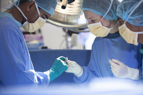 Chirurgen beugen sich über den Patienten auf dem Operationstisch, lizenzfreies Stockfoto