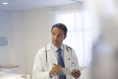 Doctor writing on clipboard in hospital - CAIF03256