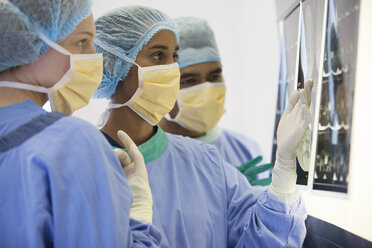 Surgeons examining x-rays in operating room - CAIF03264