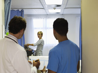 Arzt und Krankenschwester beobachten Patientenpackung im Krankenhauszimmer - CAIF03290