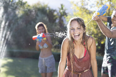 Friends playing with water guns in backyard - CAIF03313