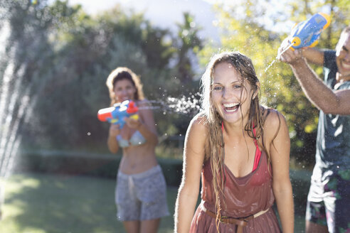Freunde spielen mit Wasserpistolen im Hinterhof - CAIF03313