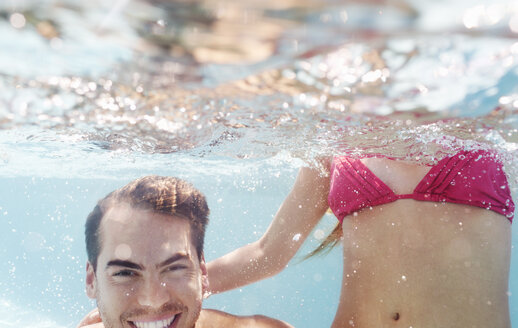 Couple playing in swimming pool - CAIF03316