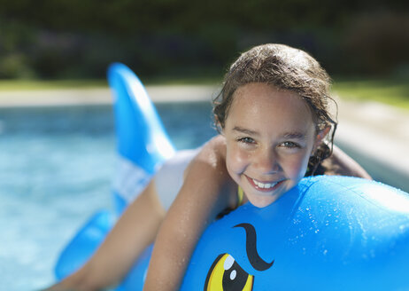 Mädchen reitet auf aufblasbarem Spielzeug im Schwimmbad - CAIF03322