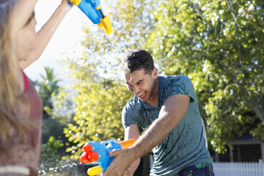 Couple playing with water guns in backyard - CAIF03352