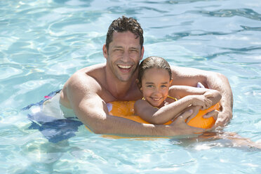 Father and daughter relaxing in swimming pool - CAIF03361