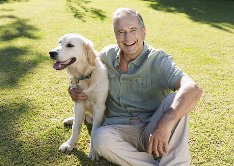 Älterer Mann umarmt Hund im Hinterhof, lizenzfreies Stockfoto