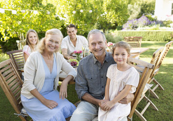 Family smiling at table outdoors - CAIF03381