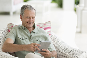 Älterer Mann benutzt Tablet-Computer auf Veranda - CAIF03384