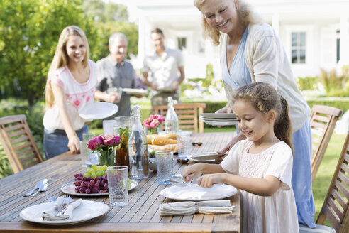 Familie deckt Tisch im Freien - CAIF03387